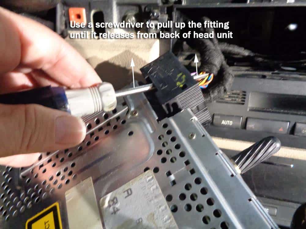 BMW E46 radio replacement - Use a screwdriver to raise the wiring harness the rest of the way.