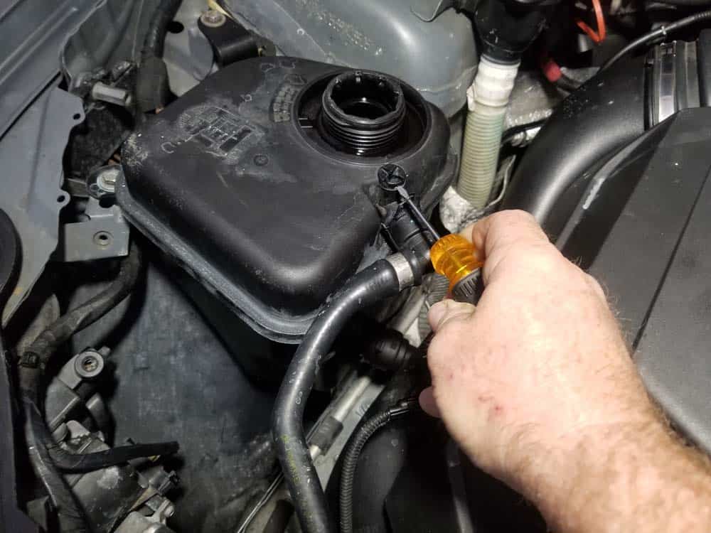 bmw e90 water pump replacement - Release the metal locking clip on the expansion tank vent line