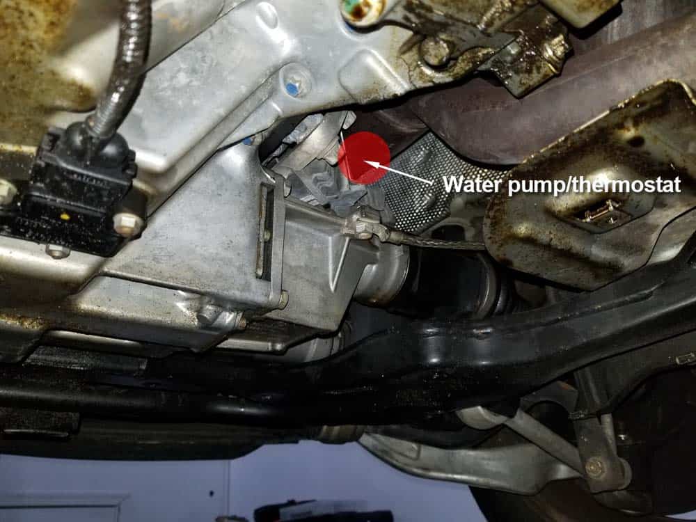 Locate the back of the water pump underneath the vehicle