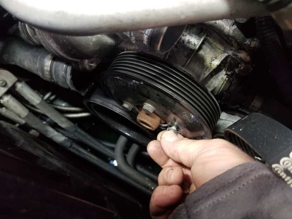 Finish removing the water pump pulley mounting bolts with your fingers