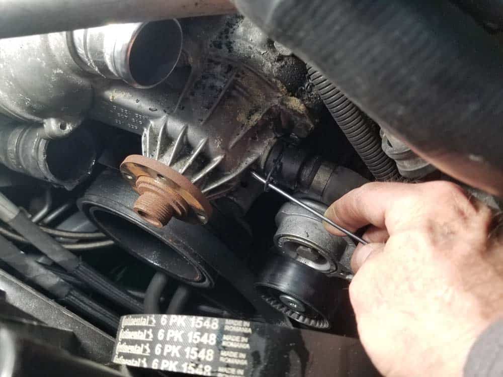 Release the lower coolant return hose from the bottom of the water pump and remove it