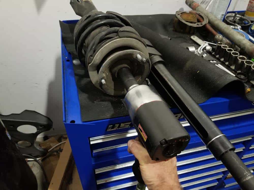 bmw e60 front strut replacement - Use an impact wrench to remove the strut shaft lock nut