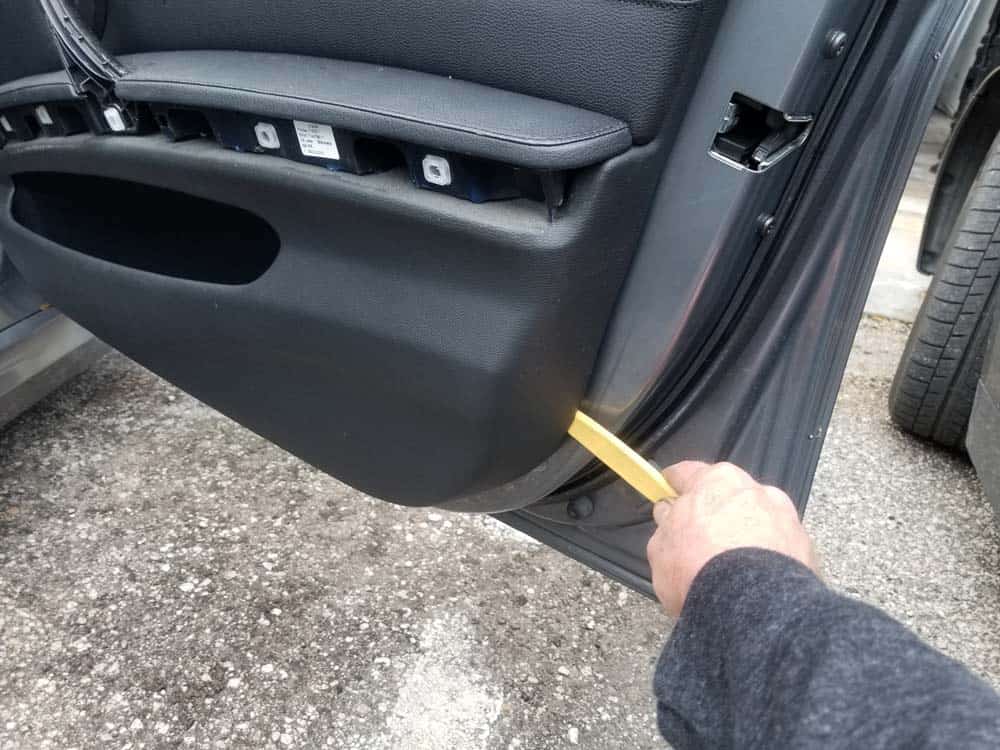 Use a plastic trim removal tool to pry the door panel loose from the frame